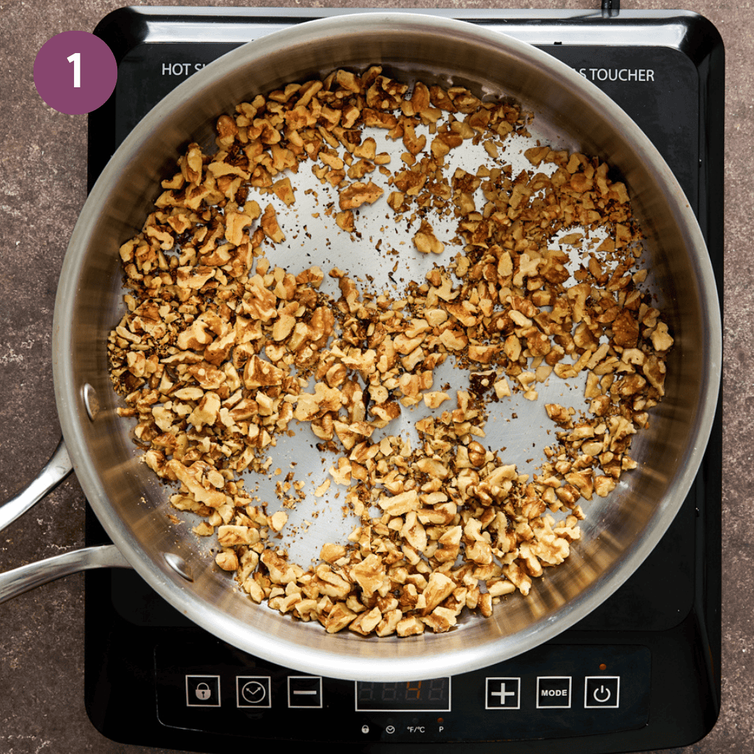 walnuts being sauteed in a frying pan.