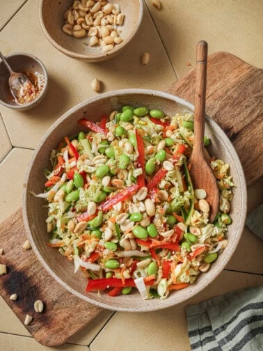 overhead view of salad with a wooden spoon on a wooden cutting board.
