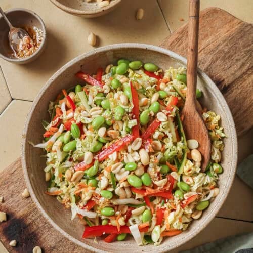 overhead view of salad with a wooden spoon on a wooden cutting board.