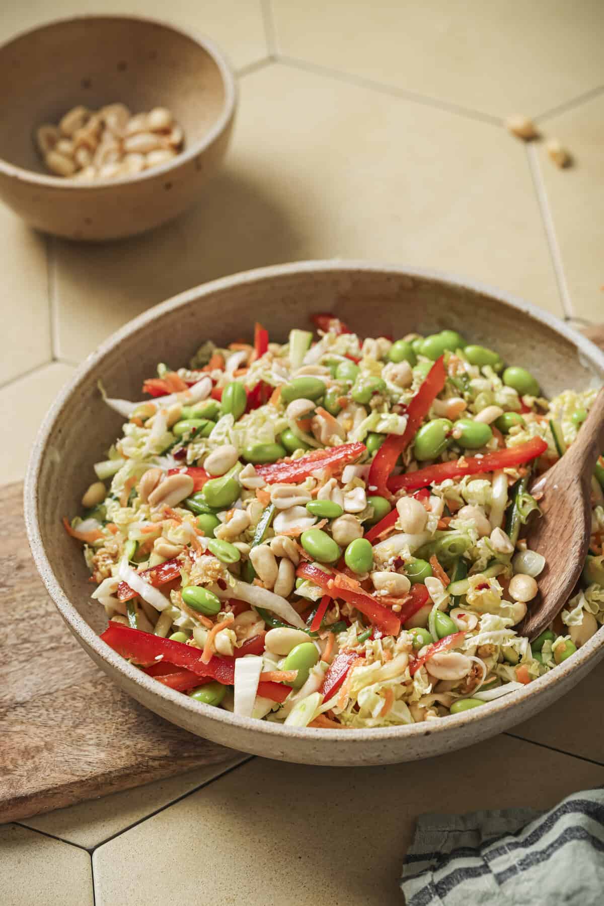 side view of bowl of salad with a wooden spoon.