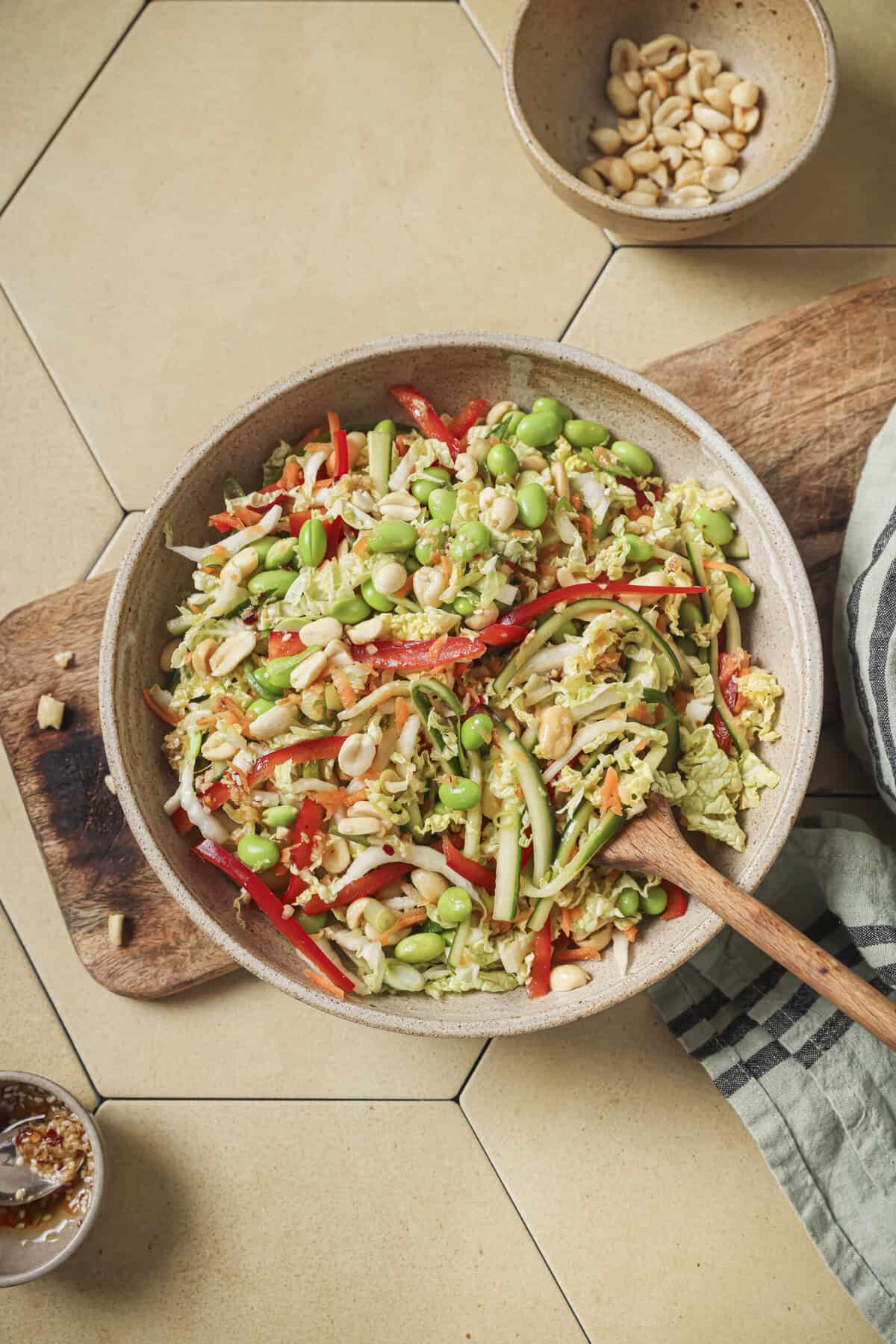 overhead view of salad with a wooden spoon on a wooden cutting board.