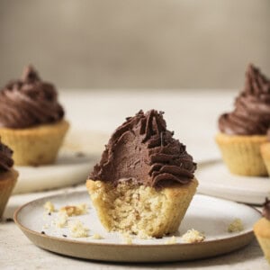 Cupcake with a bite taken out of it on a plate.