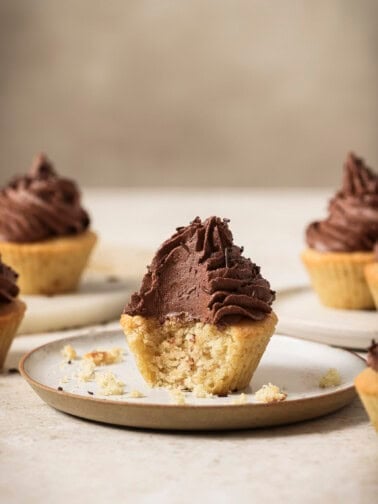 Cupcake with a bite taken out of it on a plate.
