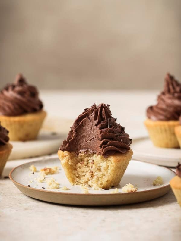 Cupcake with a bite taken out of it on a plate.
