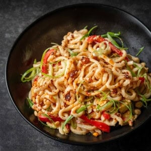 Peanut noodles with red peppers, green onions, tofu, and peanuts, drizzled with chili oil.