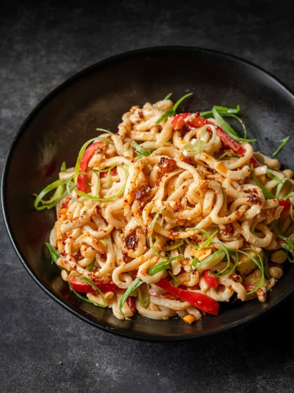 Peanut noodles with red peppers, green onions, tofu, and peanuts, drizzled with chili oil.