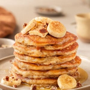 Side view of a tall stack of banana pancakes on a plate.