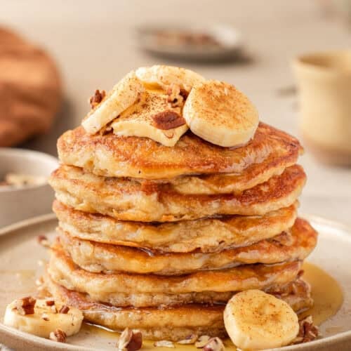 Side view of a tall stack of banana pancakes on a plate.