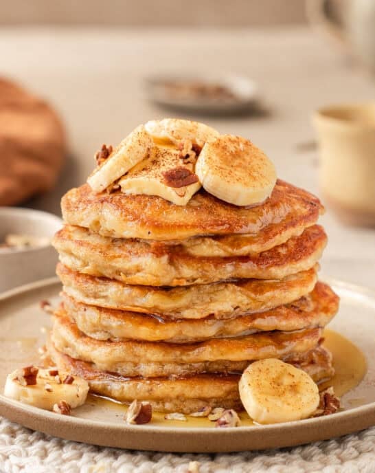 Side view of a tall stack of banana pancakes on a plate.