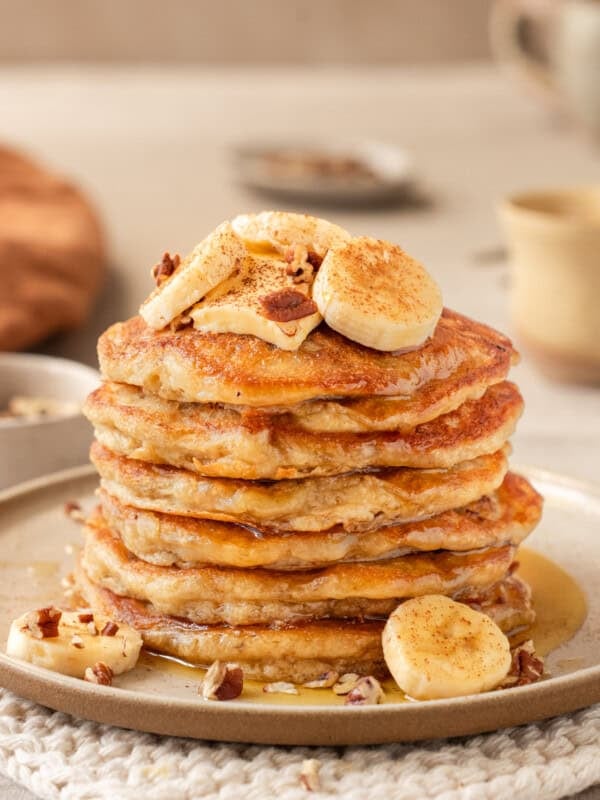 Side view of a tall stack of banana pancakes on a plate.