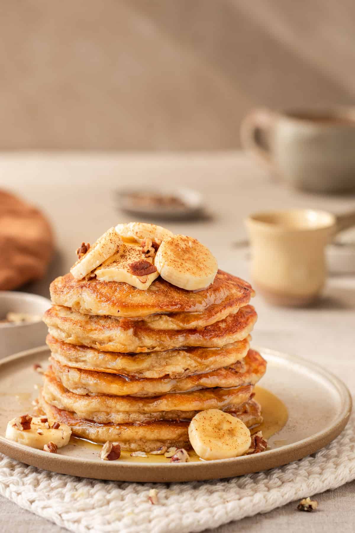 Side view of a tall stack of banana pancakes on a plate.