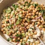 Angled overhead shot of chickpea salad in a beige bowl with a spoon.