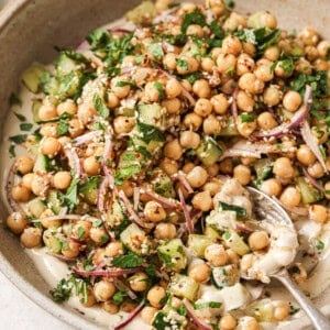 Angled overhead shot of chickpea salad in a beige bowl with a spoon.