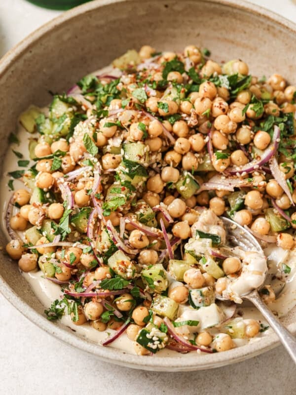 Angled overhead shot of chickpea salad in a beige bowl with a spoon.