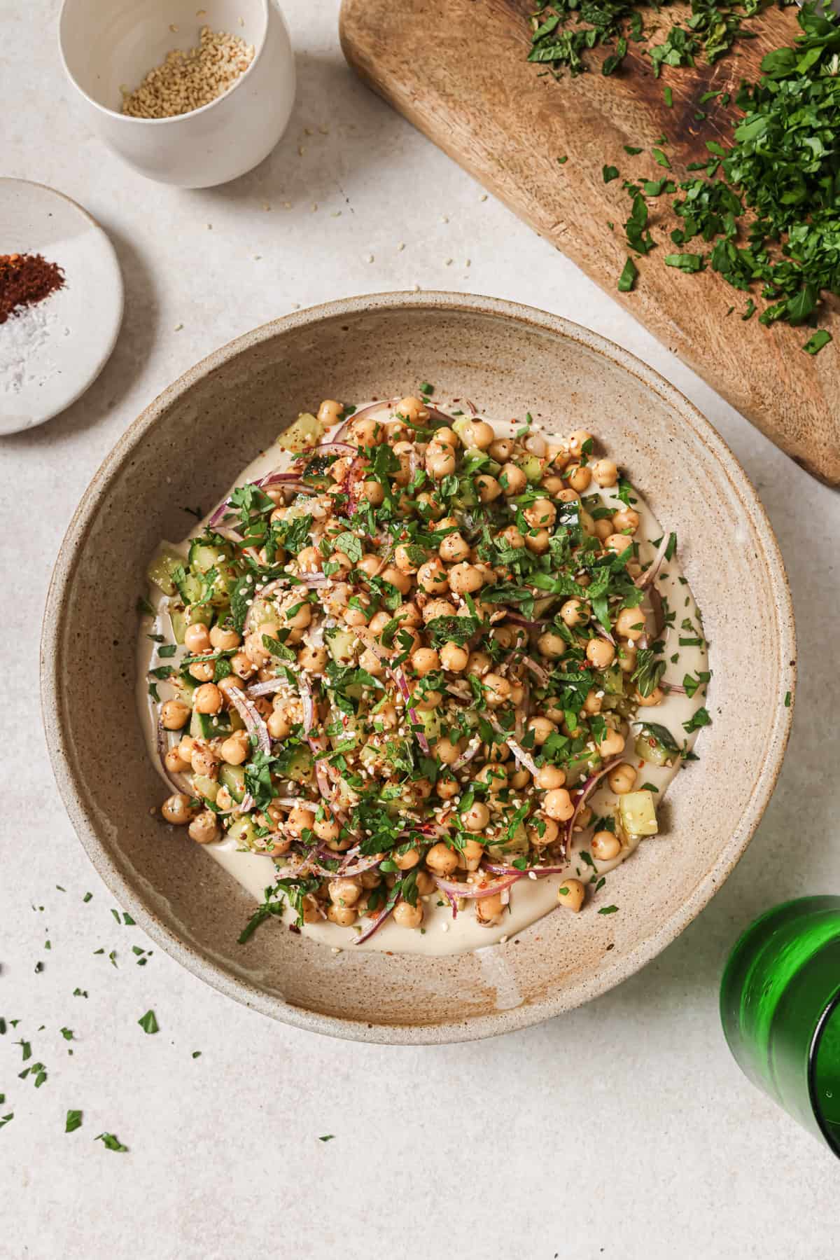 Overhead view of chickpea salad in a bowl with scattered herbs and prep items.