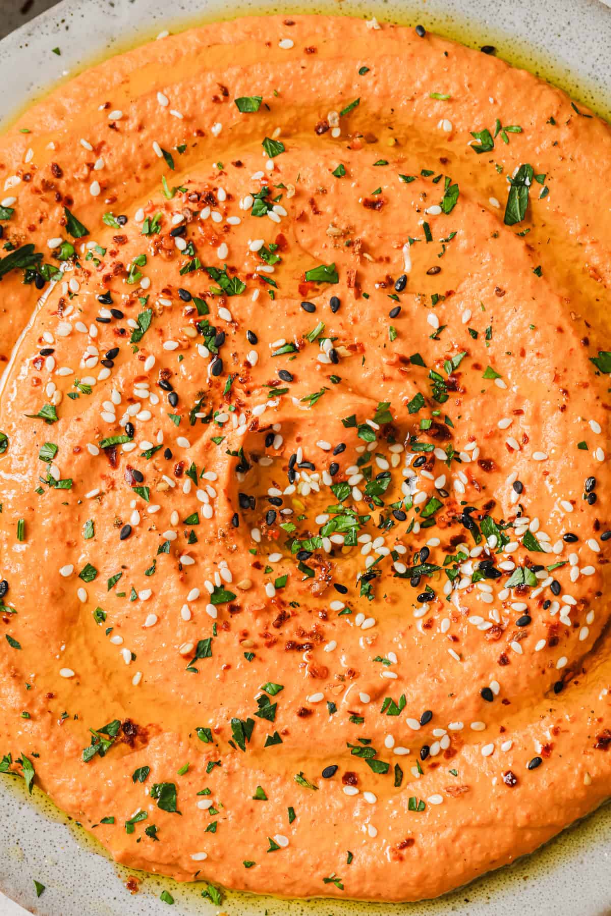 close up of roasted red pepper hummus on a plate.