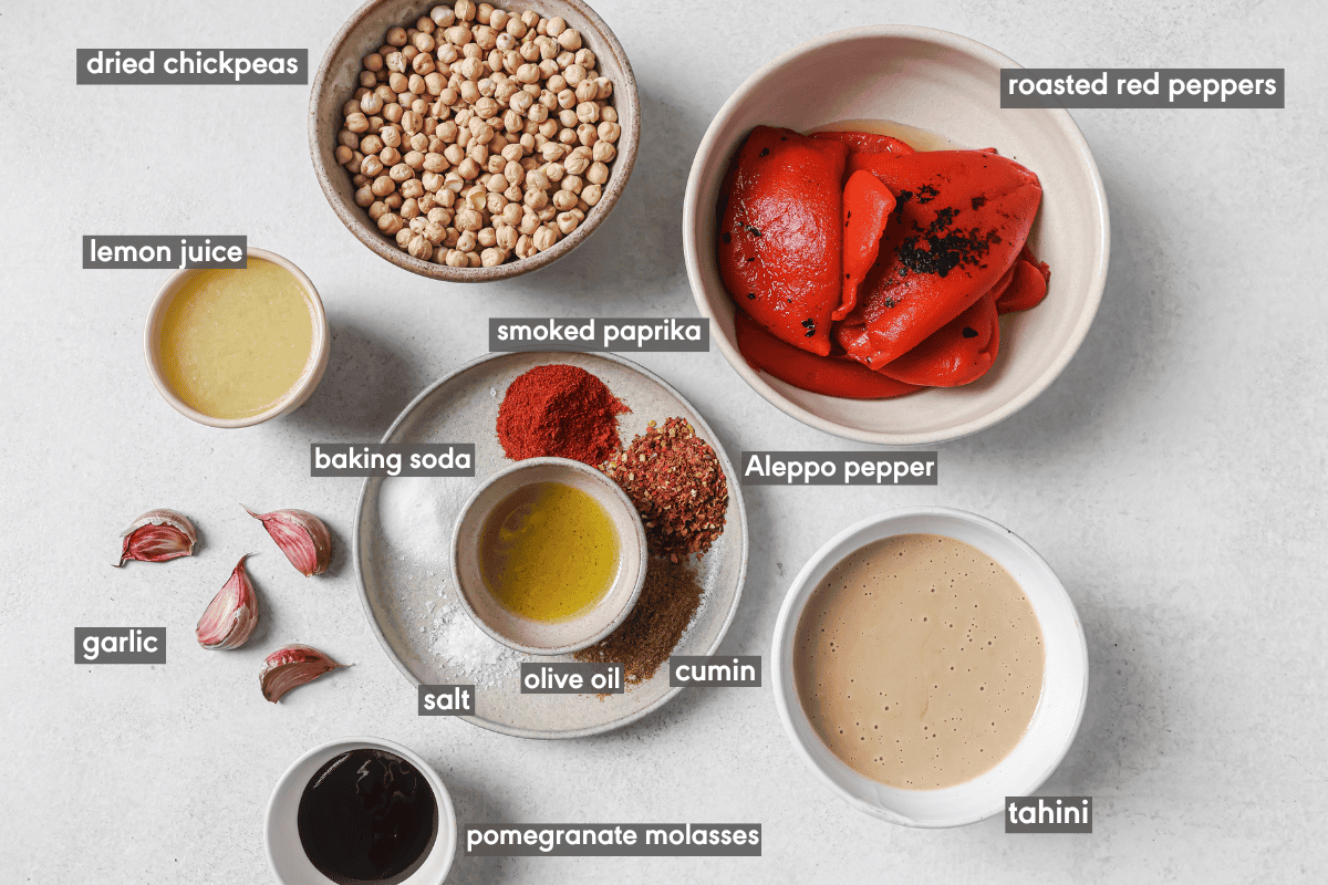 Ingredients for roasted red pepper hummus in various bowls on a table.