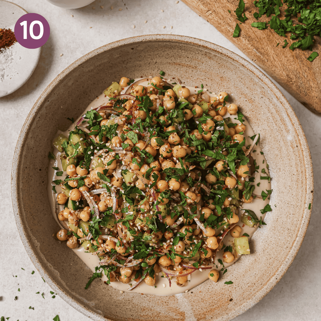 plated chickpea salad over tahini dressing in bowl.