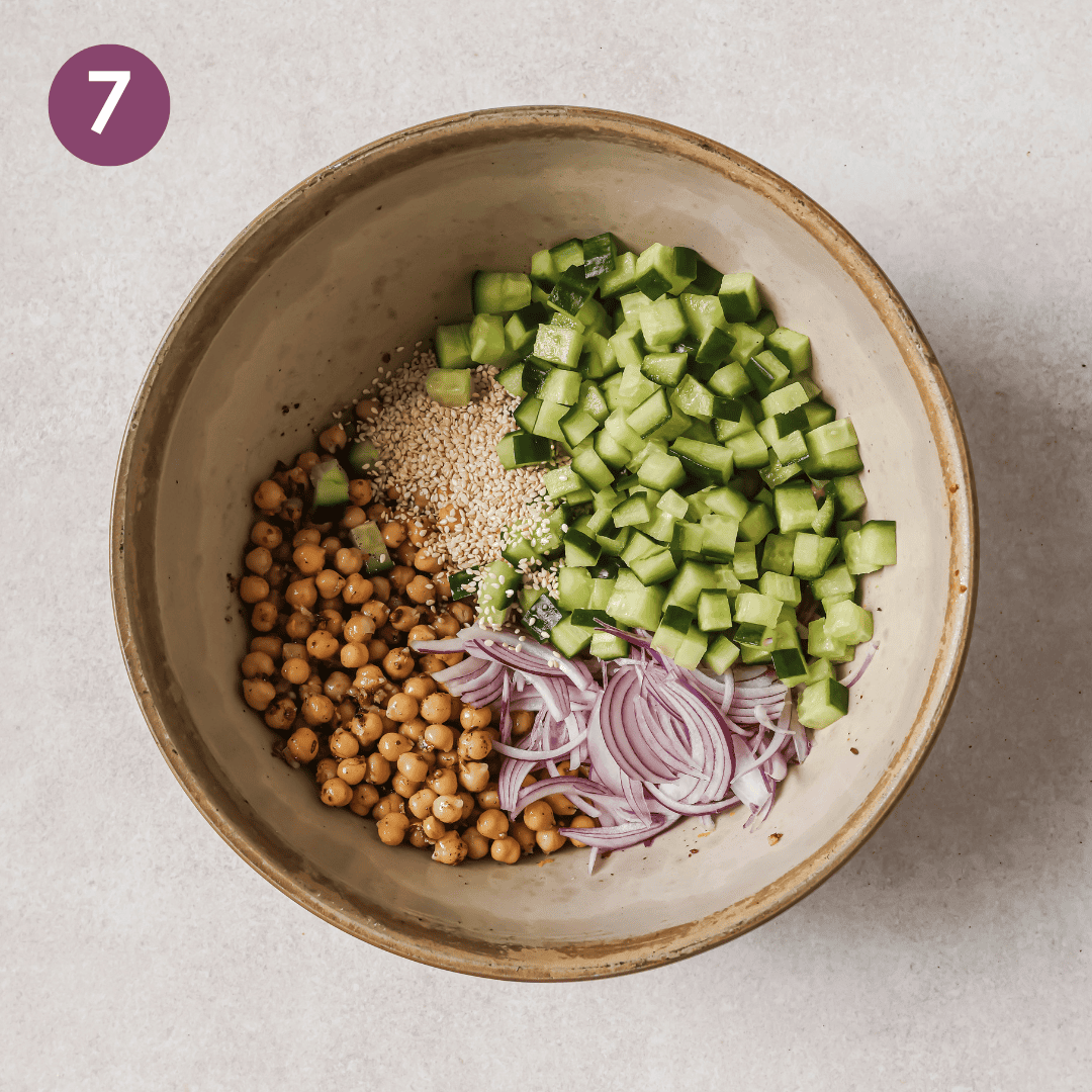 chickpeas, cucumber, red onion and sesame seeds in a bowl before being mixed.