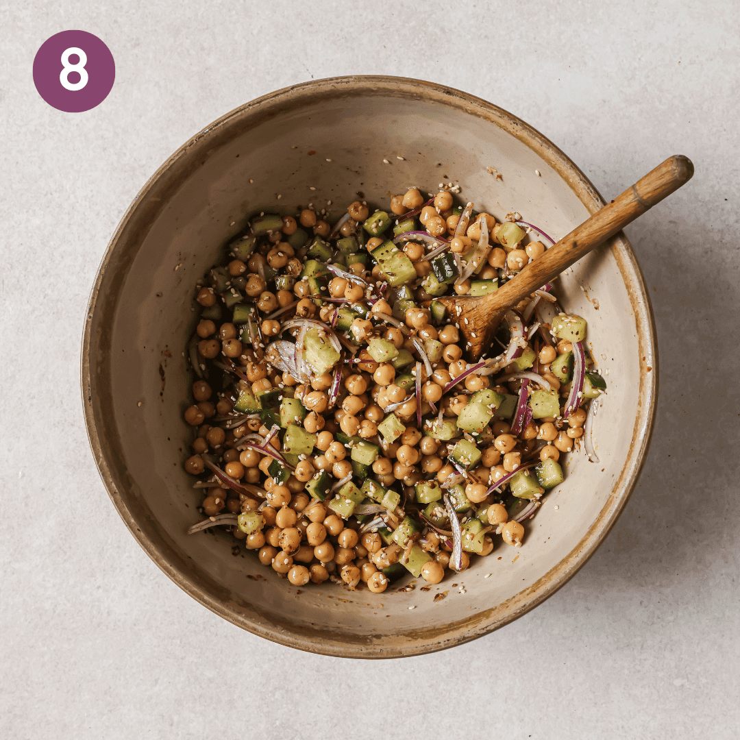 chickpeas, cucumber, red onion and sesame seeds in a bowl after being mixed.