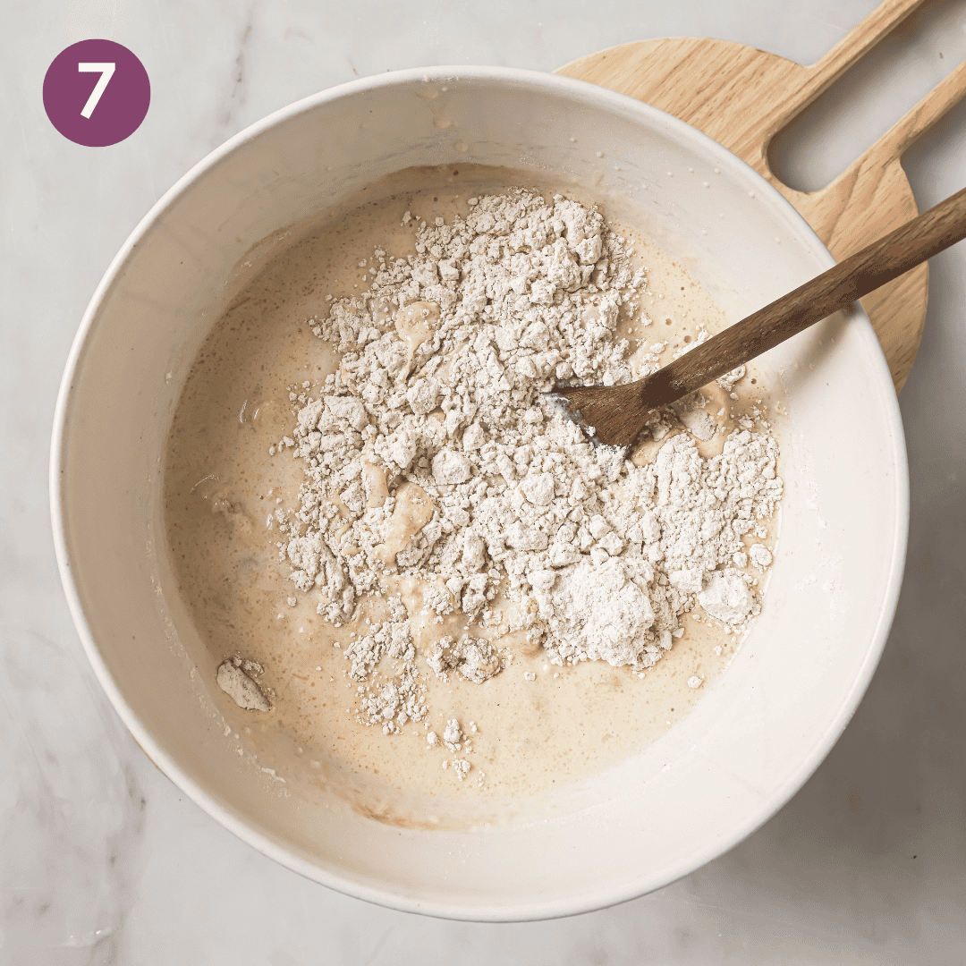Person adding dry ingredients to wet ingredients.