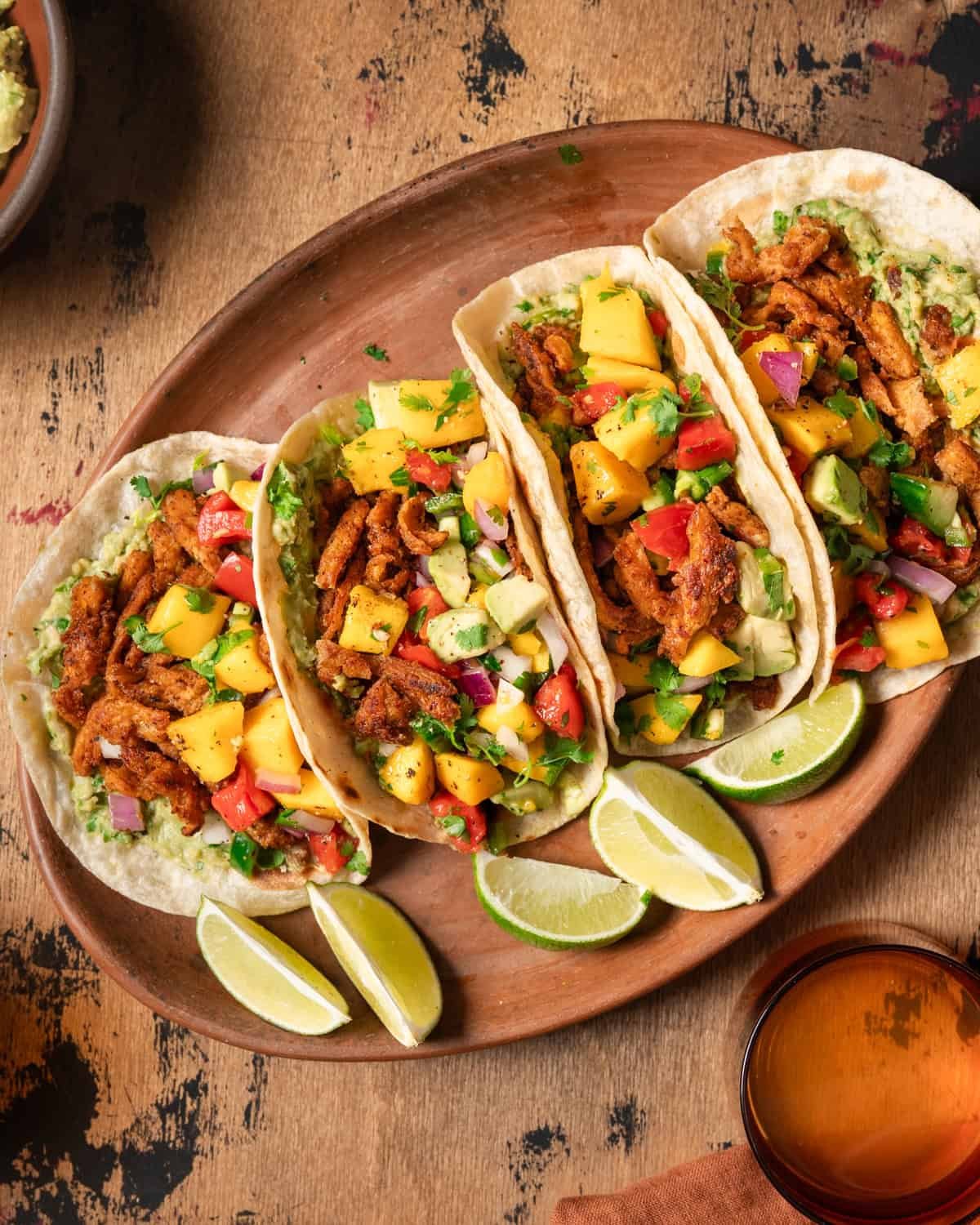 Overhead view of four vegan tacos with soy curls on a platter.