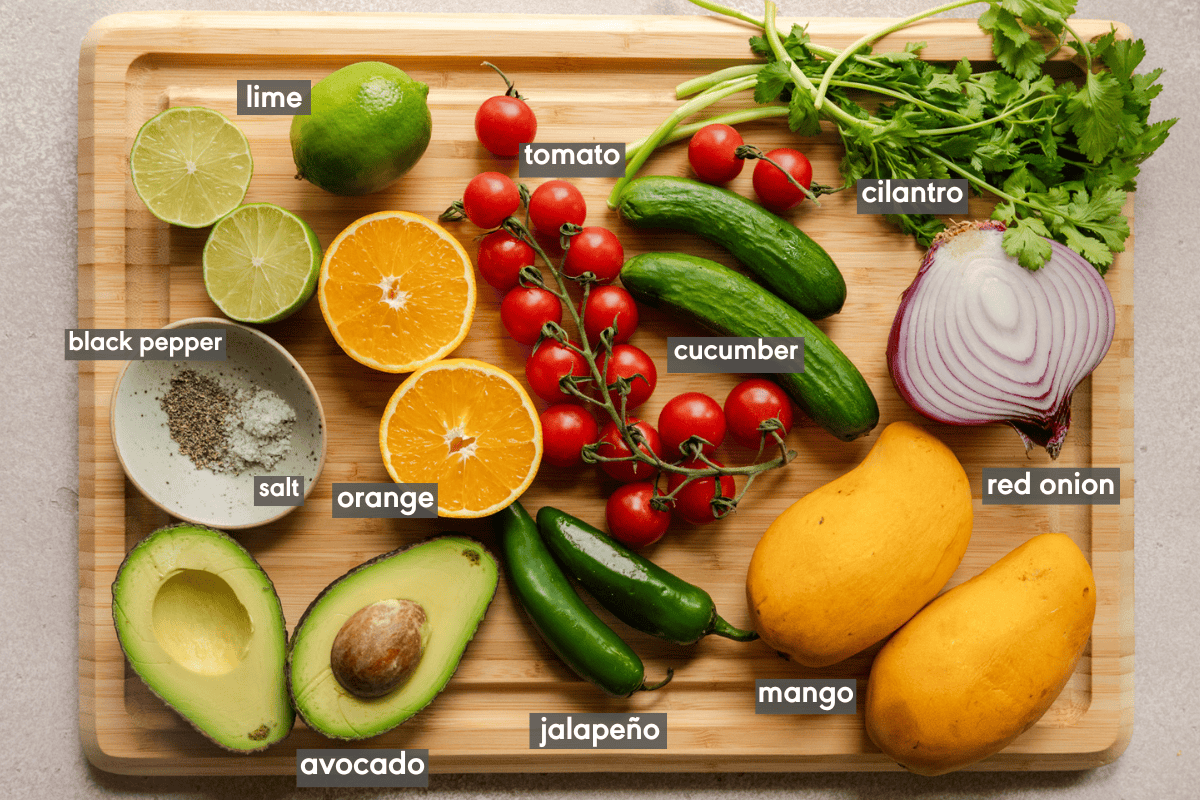 ingredients for mango avocado salsa on a wooden cutting board.