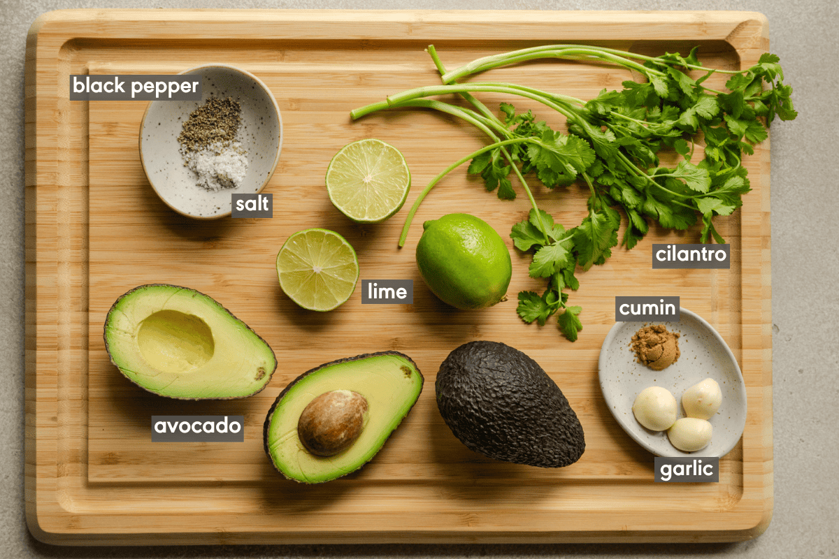 ingredients for simple guacamole on a wooden cutting board.