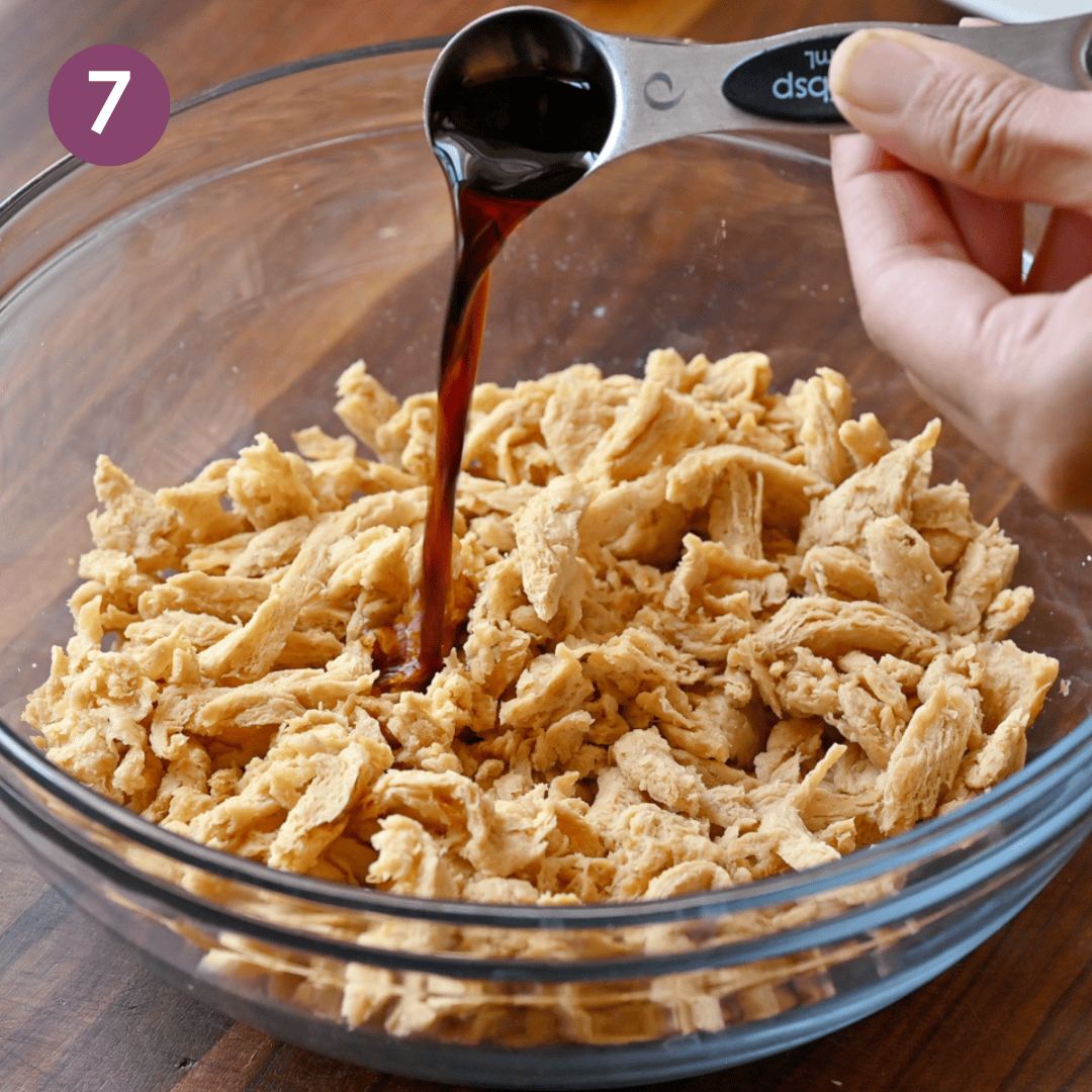 Person pouring tamari into the soy curls in a bowl,