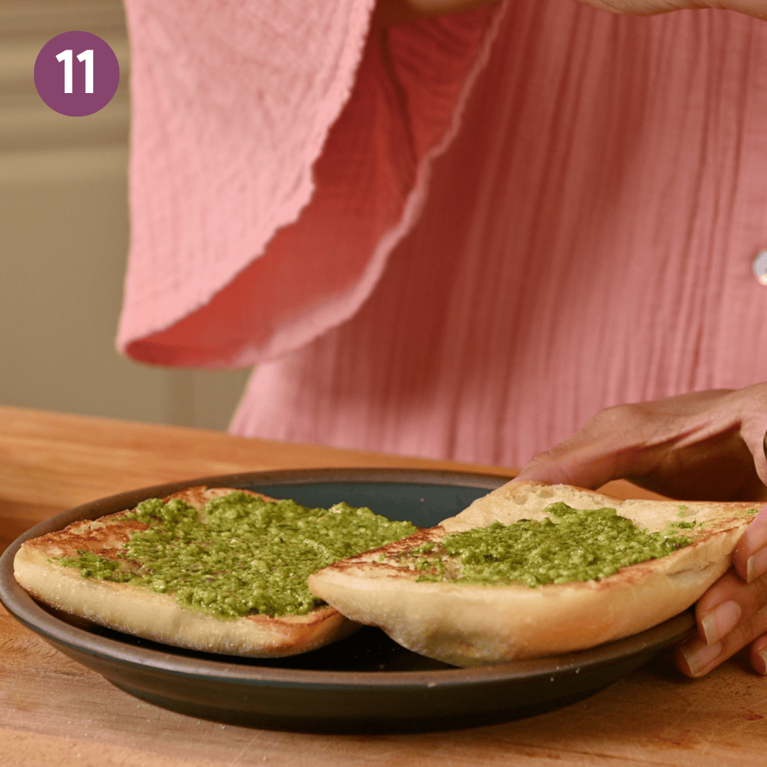Pesto slathered on two slices of bread on a plate.