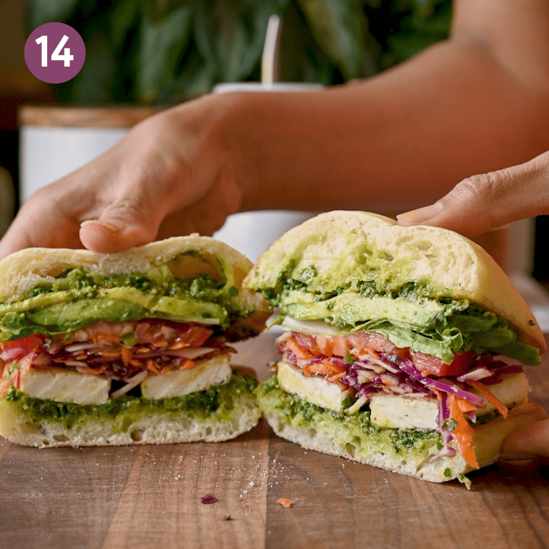 Finished sandwich cut in half on a wooden cutting board.