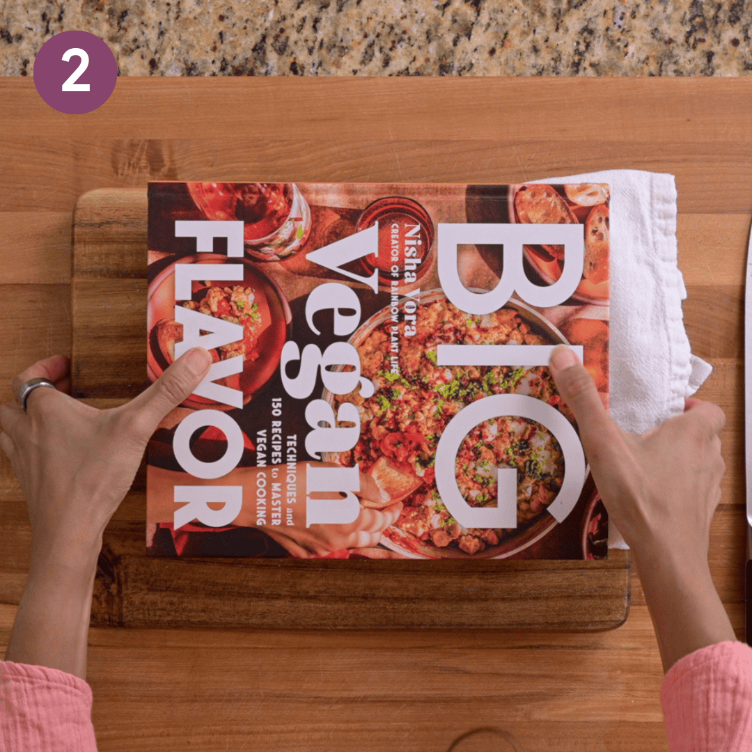 Person using a cookbook to press the tofu.