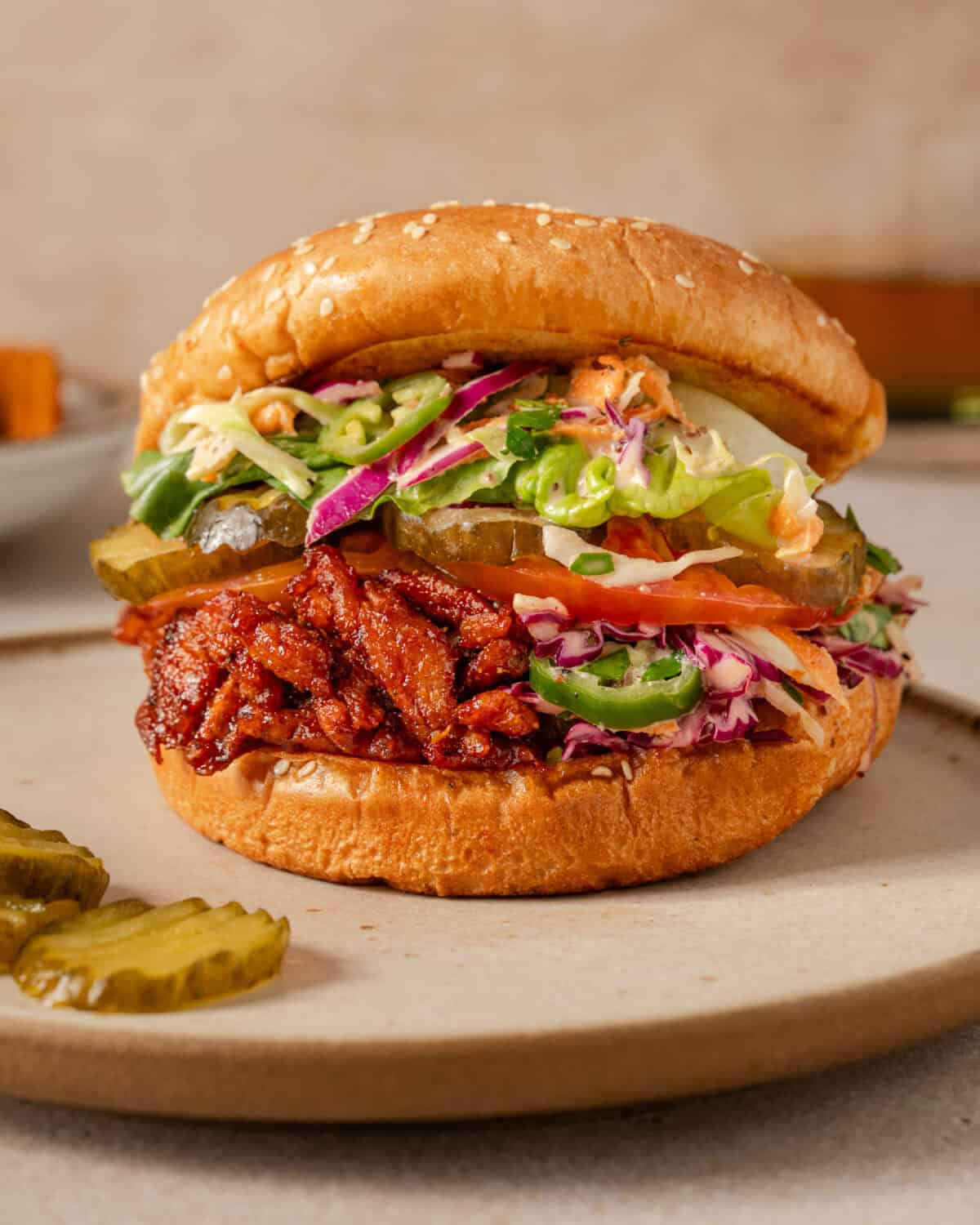 close up side view of one vegan bbq pulled pork sandwich on a plate.