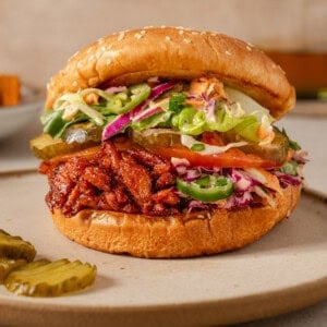 close up side view of one vegan bbq pulled pork sandwich on a plate.