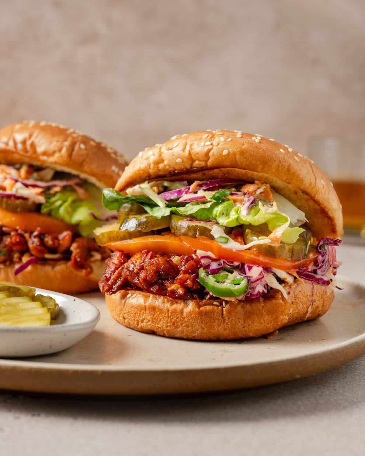 side view of two vegan pulled pork sandwiches on a plate.