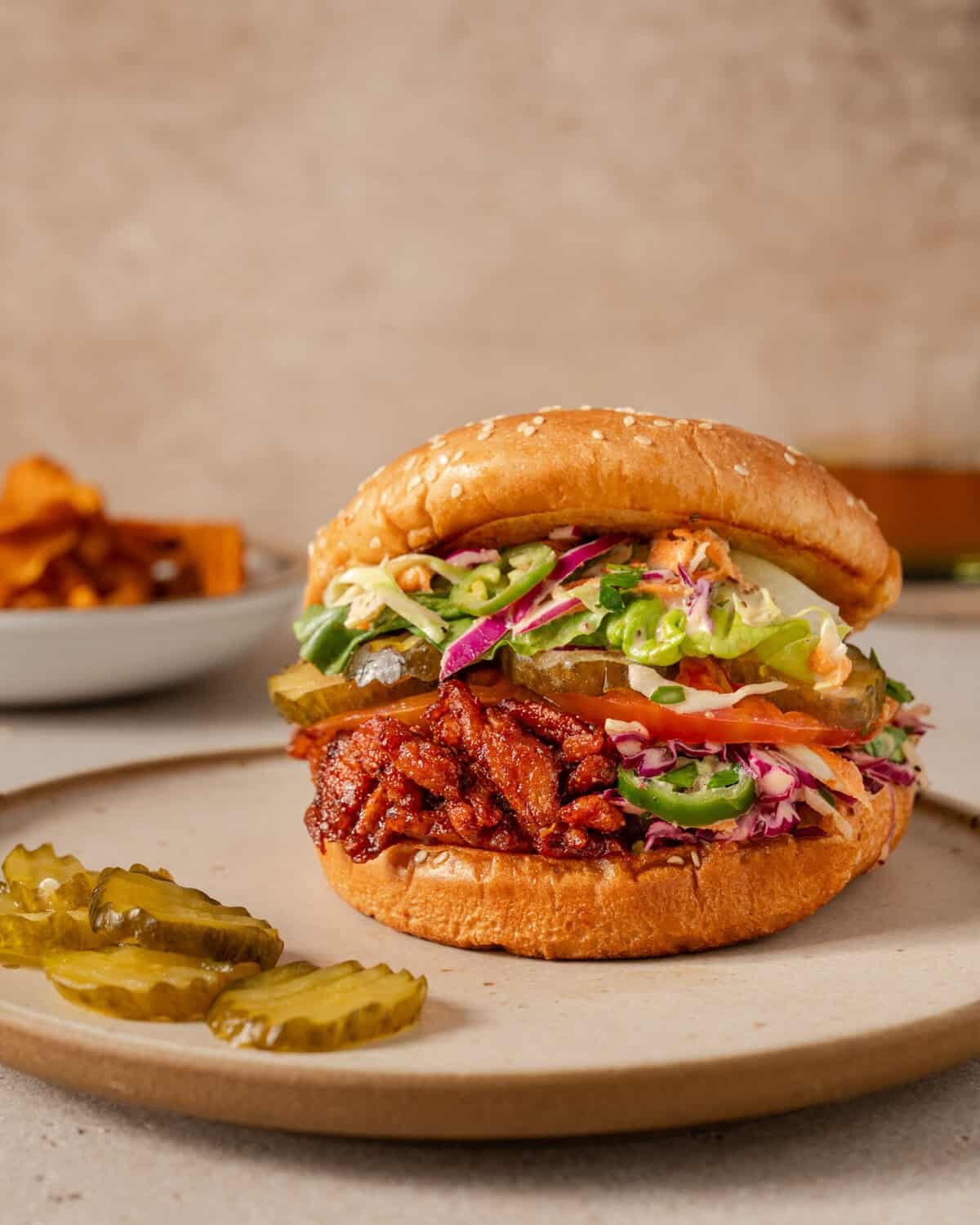 side view of one vegan bbq pulled pork sandwich on a plate.
