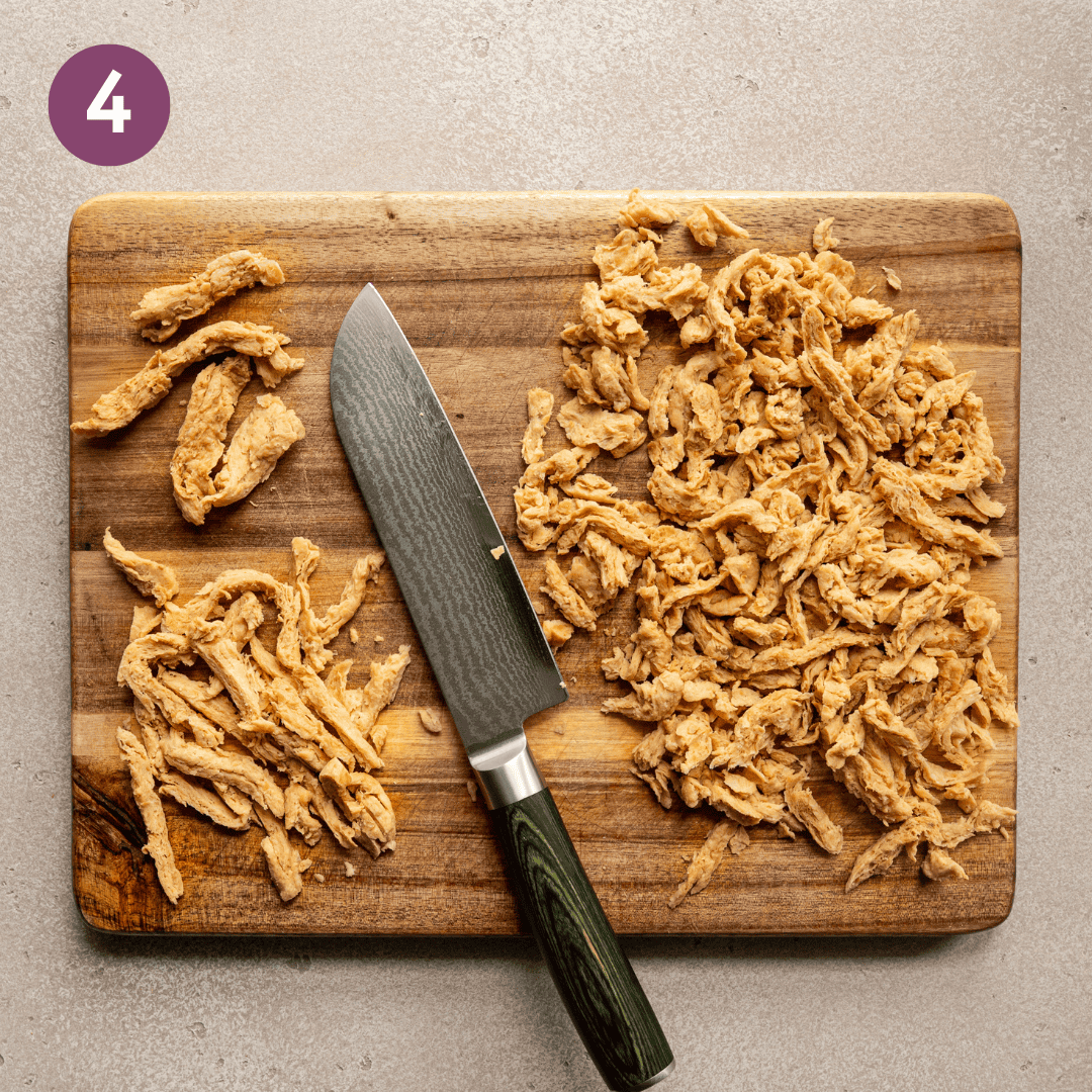 full soy curls, sliced soy curls and a chefs knife on a wooden cutting board.
