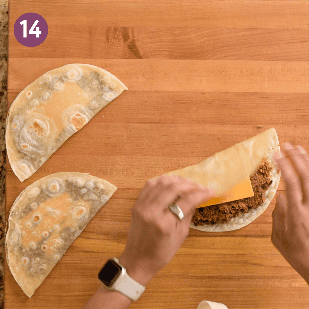 person folding tortillas in half over the cheese.