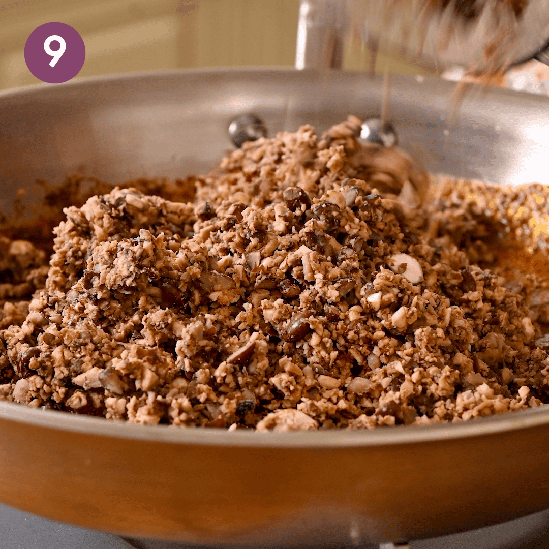 bean mushroom mixture added to spiced oil in pan.