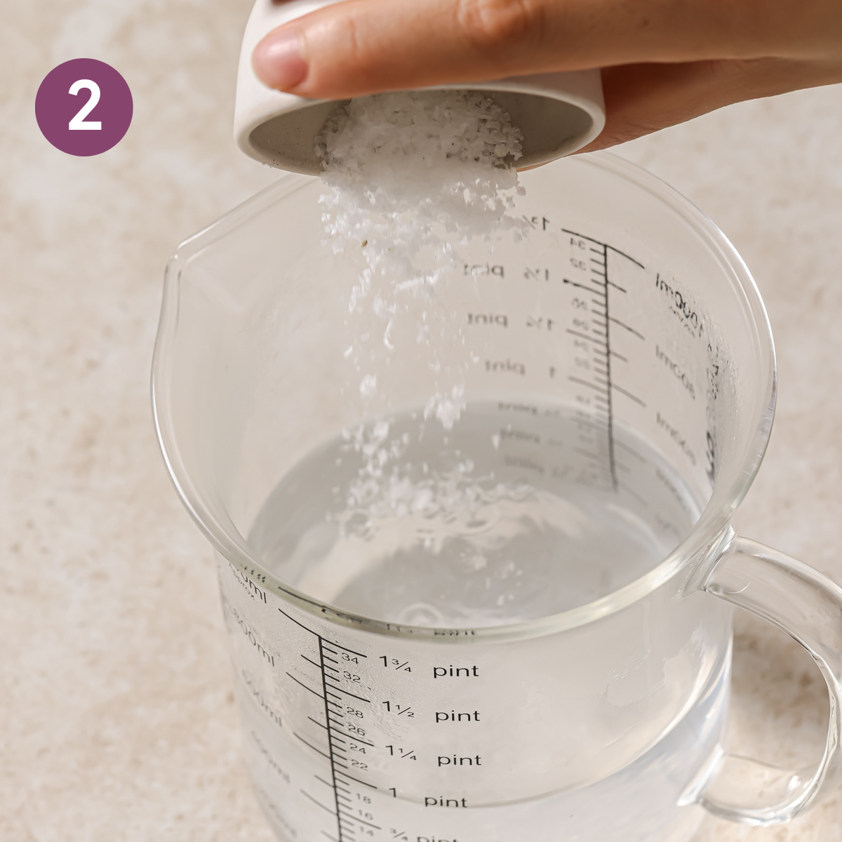 person dumping salt into a beaker of hot water.