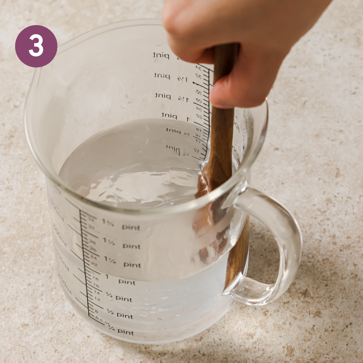 person using wooden spatula to stir salt into water.