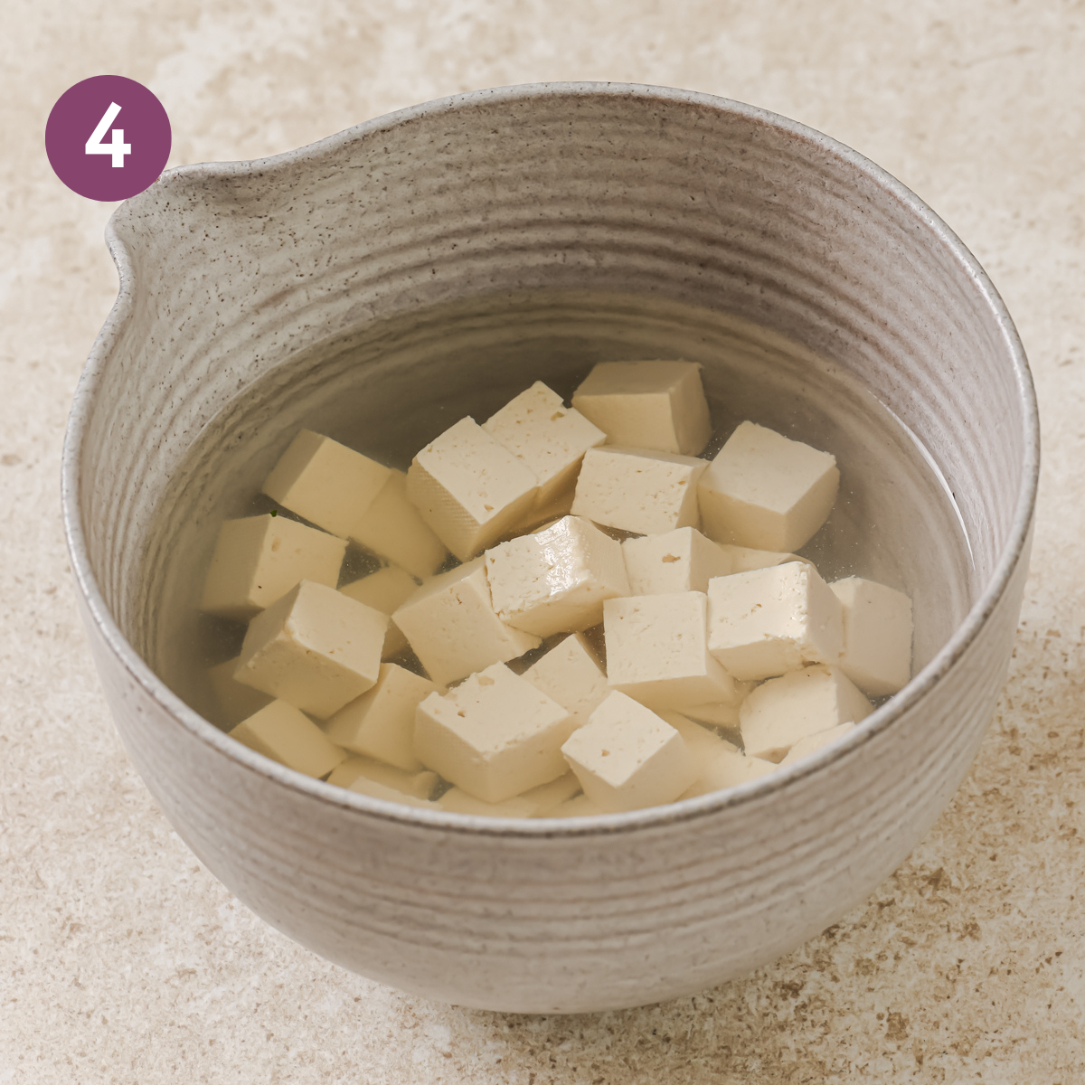 tofu cubes soaking in hot salt water.