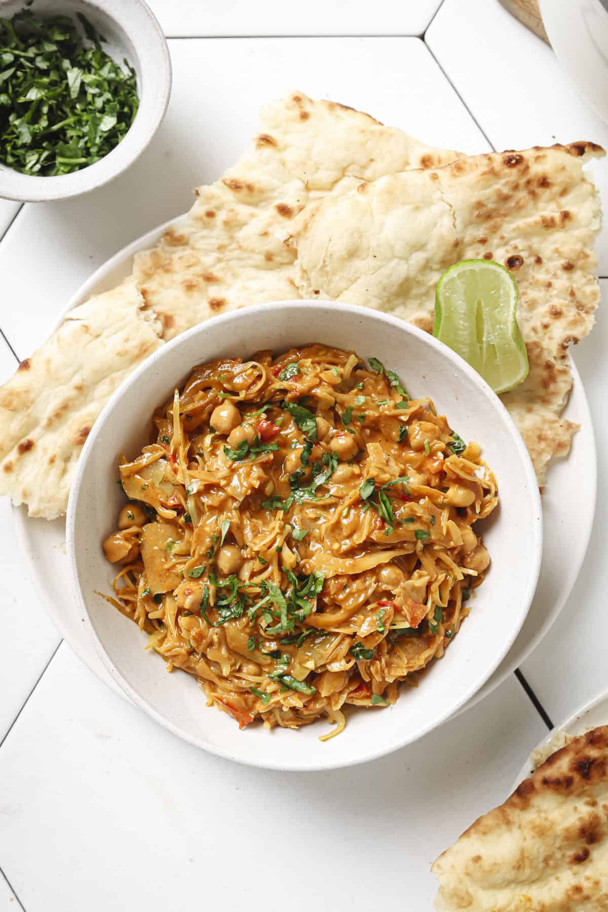 bowl of curry with a side of roti and a lime wedge.