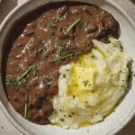 Gravy and mashed potatoes with a pat of butter in a bowl.