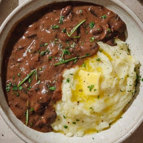 Gravy and mashed potatoes with a pat of butter in a bowl.