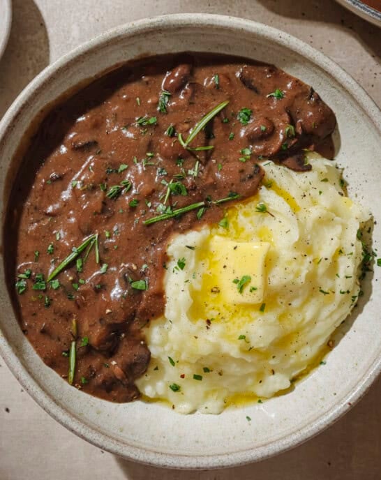 Gravy and mashed potatoes with a pat of butter in a bowl.