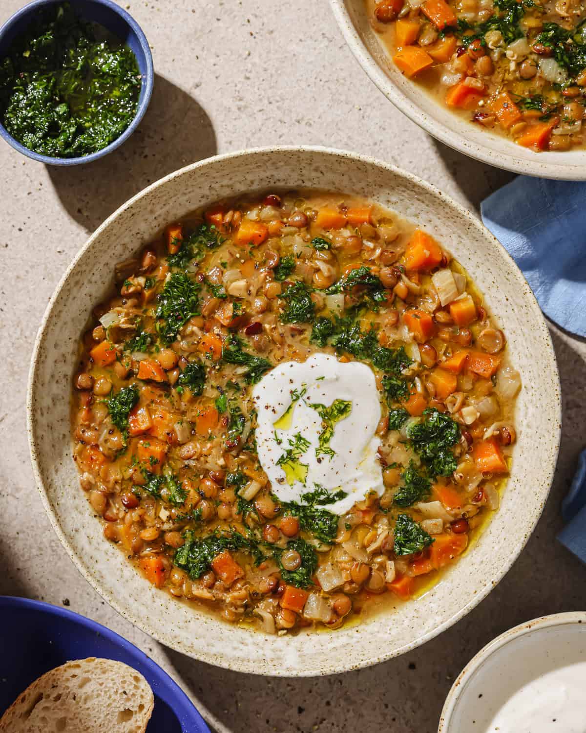 Lentil soup in a bowl, garnished with fresh herbs and yogurt sauce.