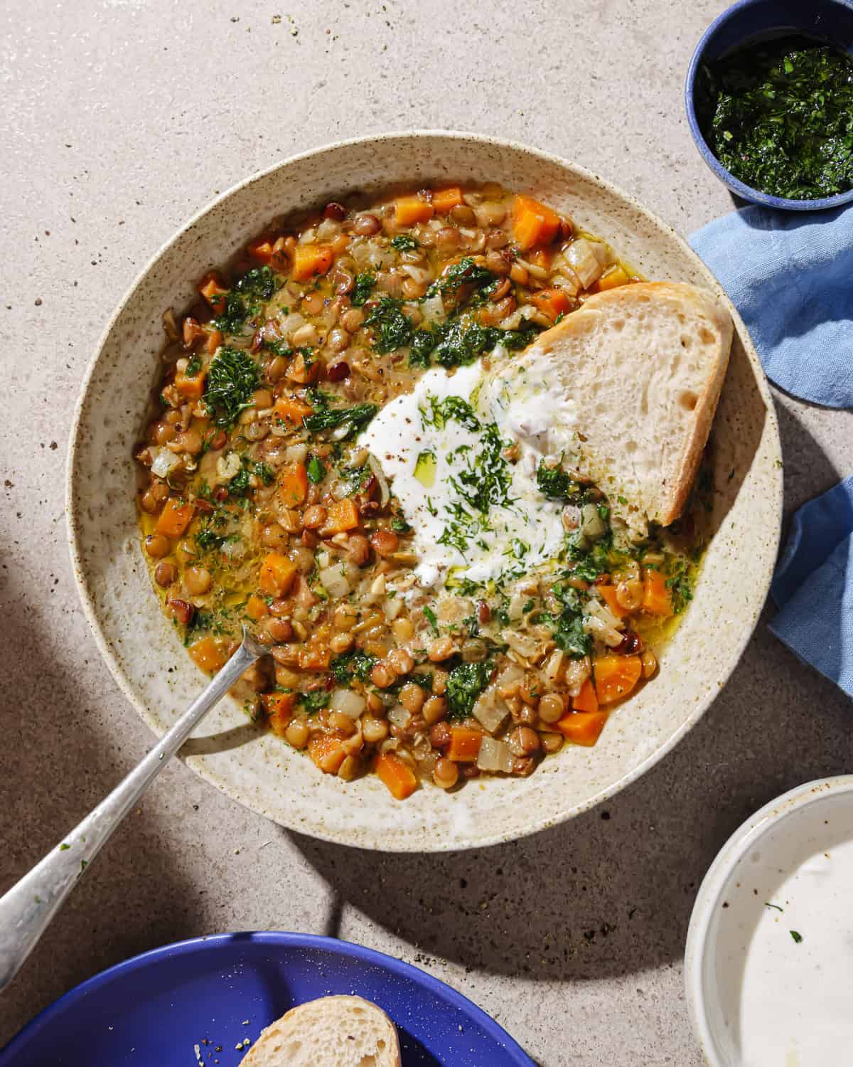 overhead view of lentil soup in a bowl next to small bowl of herby oil.