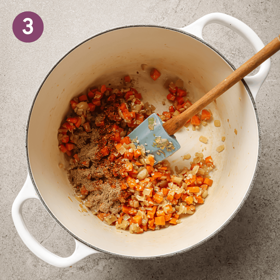 spices added to cooked carrot onion mixture in a dutch oven.
