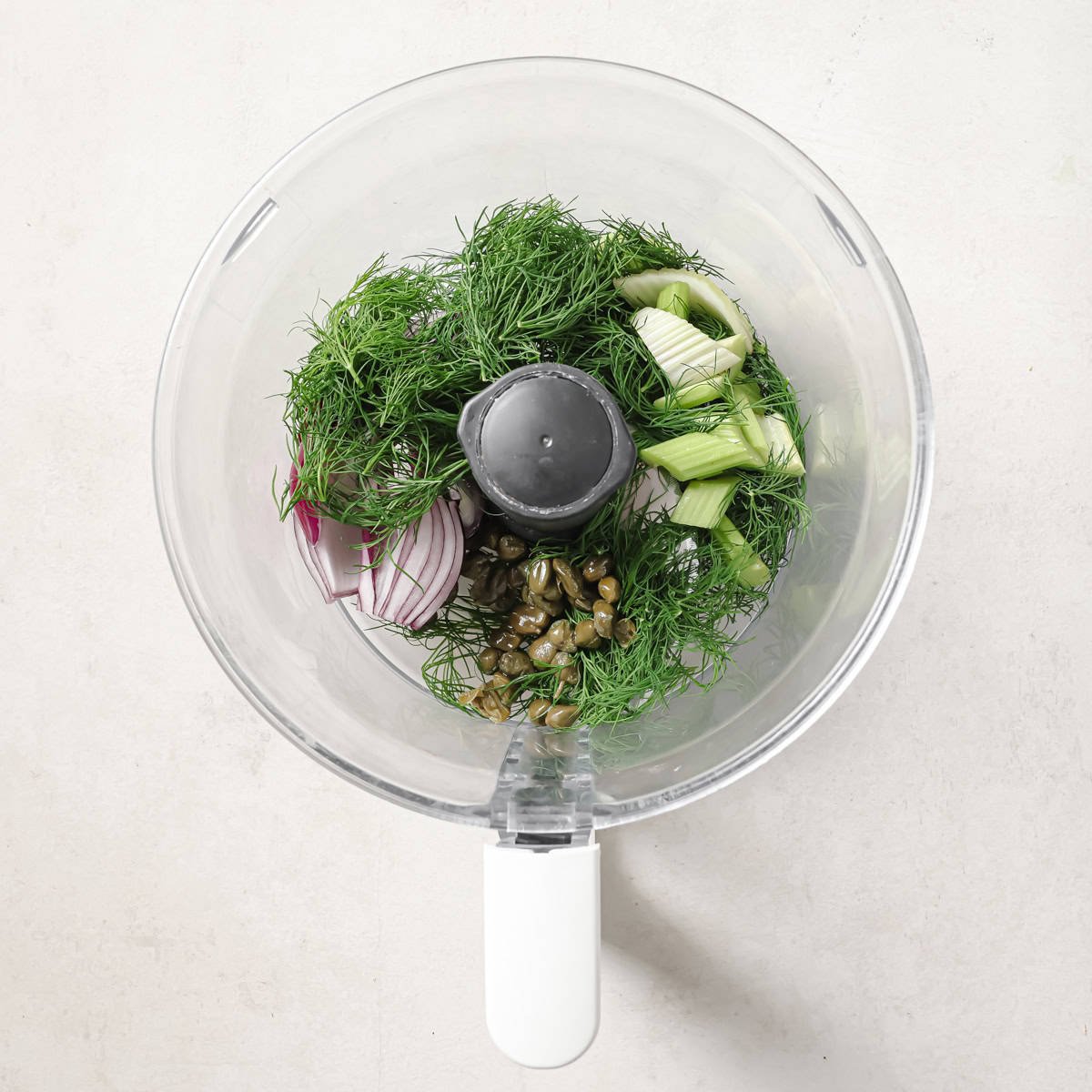 onion, celery, dill, and capers in a food processor before being pulsed.